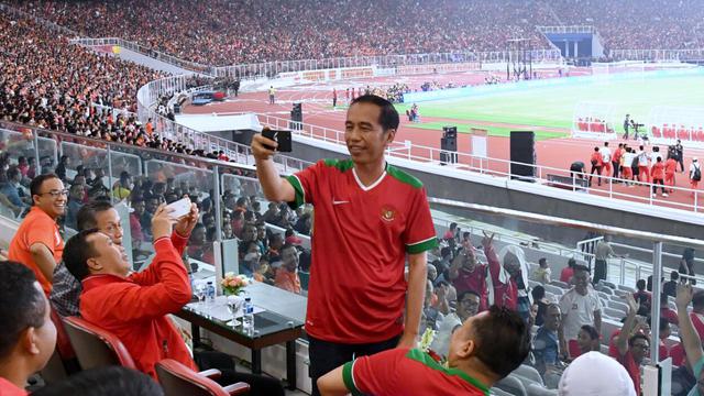 Presiden Joko Widodo (Jokowi) tampak asyik membuat vlog dengan kamera handphone saat menyaksikan laga final Piala Presiden 2018 antara Persija Jakarta vs Bali United di Stadion Utama Gelora Bung Karno, Sabtu (17/2). - Biro Pers Setpres